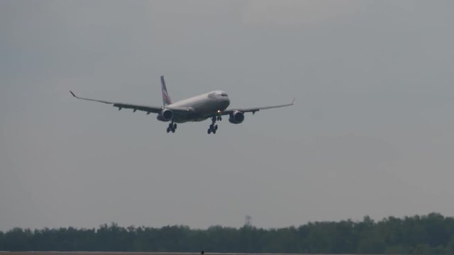 Airbus A330 lose height above runway for landing. Blurred view through heat haze