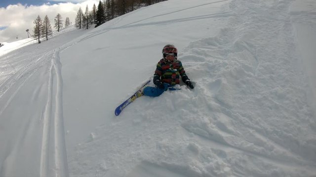 Freeride skiing. Little boy skiing in the wild. A 5 year old child enjoys a winter holiday in the Alpine resort. Stabilized shot. Slow motion.