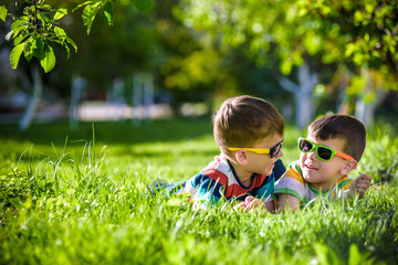 Happy smiling boy sibling brother relaxing on the grass. Close up view with copy space.