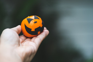 an oranges pumpkin face painting with scary on halloween party day on hand with blur background.