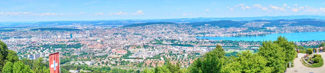 Swiss banner fluttering in the wind. City of Zurich in the background.