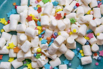 marshmallow and colorful festive sprinkling on a blue plate. macro.