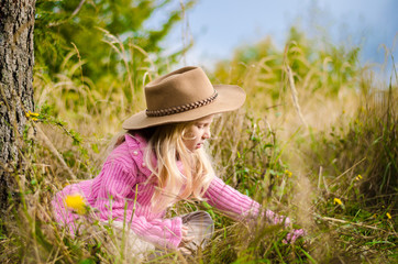 adorable child with hat in autumn forest smiling and relaxing