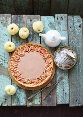 Fototapeta na wymiar Homemade apple rose pie with cream filling served with tea and raw organic apples on old wooden turquoise background
