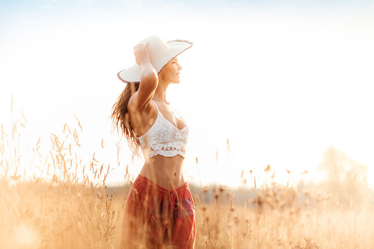 Young attractive girl in field at sunset