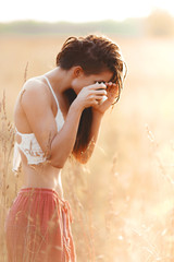 Young attractive girl with camera in field at sunset