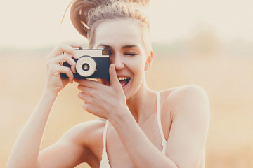 Young attractive girl with camera in field at sunset