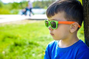 Portrait of smart little boy wearing sunglasses smirking.