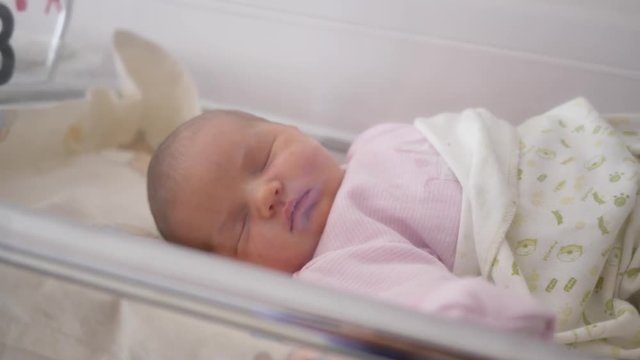 Newborn baby girl is sleeping in the maternity hospital bed