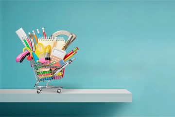 Stationery objects in mini supermarket cart on  background
