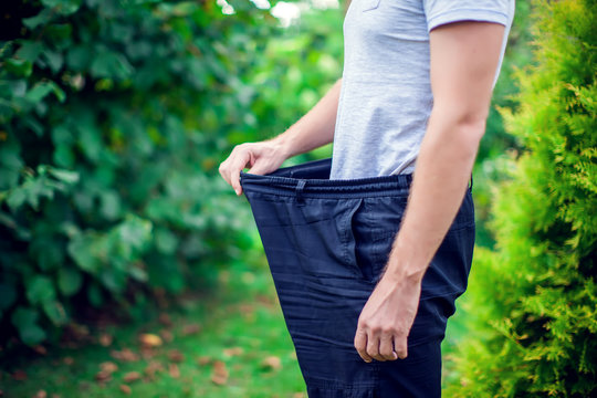 Young man wearing big loose jeans - weight loss concept