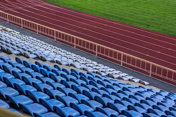 Obraz premium aerial concept shot of football stadium arena complex from above with plastic empty blue seats red running track with marking and green field for soccer game 