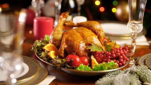 Closeup 4k footage of Christmas dinner table with baked chicken. Glowing colorful lights on backgorund