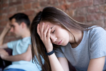 Man and woman sitting on different sides of each other, offended. Woman with headache....