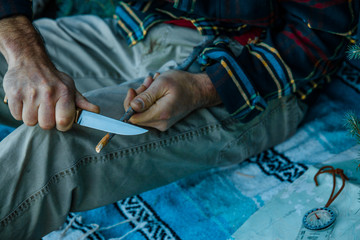 Man Carving A Stick With A Knife While Wilderness Camping