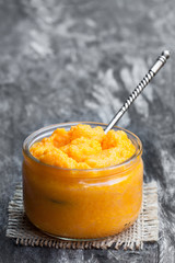 Orange  vagetables puree in glass jar on wooden table