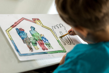 Child colouring in a sketch of a family using a paintbrush