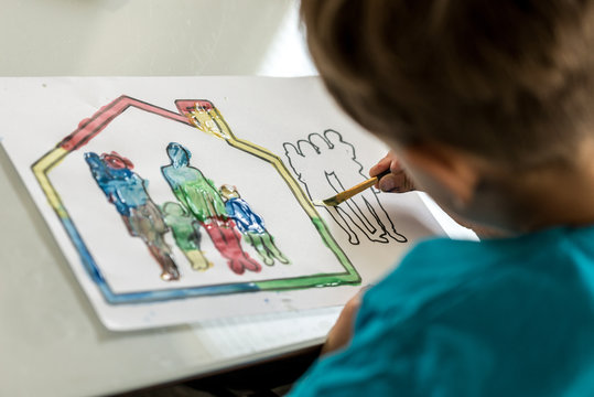 Child colouring in a sketch of a family using a paintbrush