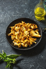 Fresh chanterelle mushrooms in a pan on a black table