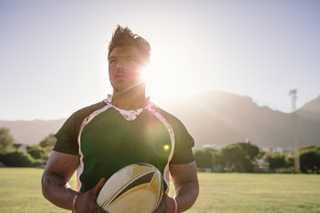 Sportsman holding a rugby ball on field