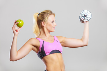 Diet fit body. Girl holds dumbbells and apple fruit - obrazy, fototapety, plakaty