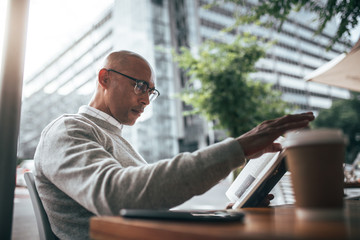 Businessman sitting at a restaurant reading book.