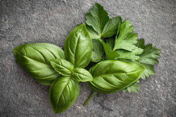 Sweet basil leaves over black stone background. Top view.