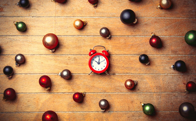 Alarm clock with Christmas baubles around on wooden table. Above view in old color style