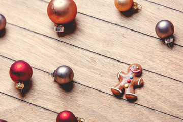 gingerbread man with Christmas baubles around on wooden table. Above view in old color style