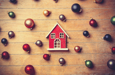 wooden house with Christmas baubles around on wooden table. Above view in old color style