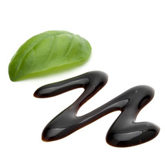 Balsamic vinegar cream and basil leaves isolated on white background. Italian salad dressing, sauce.
