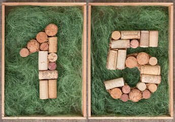 Number 15 fifteen made of wine corks on green background in wooden box