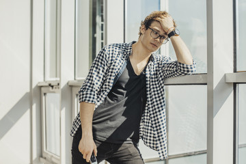 Distant plan of young man standing next to big windows at metro station.