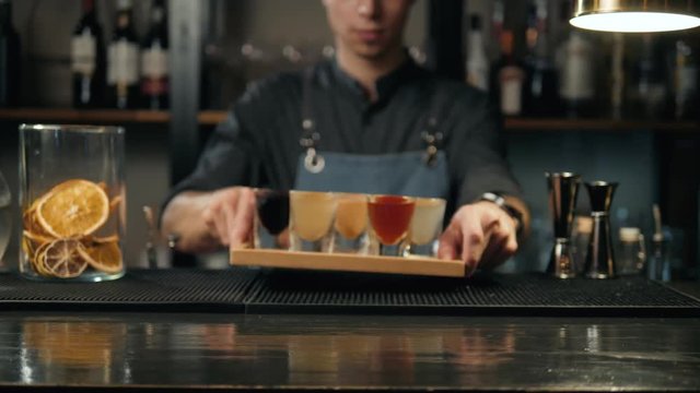 Beautiful row line of different colored alcohol cocktails bartender on a party, martini, vodka, and others on decorated catering bouquet table on open air event
