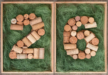 Number 26 twenty six  made of wine corks on green background in wooden box