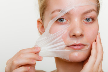 Woman removing facial peel off mask.