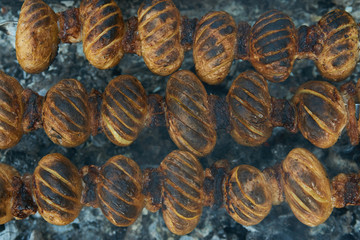 Baby potatoes grilled on skewers with lamb fat meat over coals