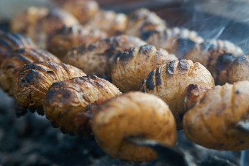 Baby potatoes grilled on skewers with lamb fat meat over coals