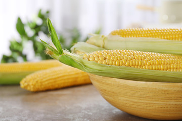 Bowl with tasty sweet corn cobs on table, closeup