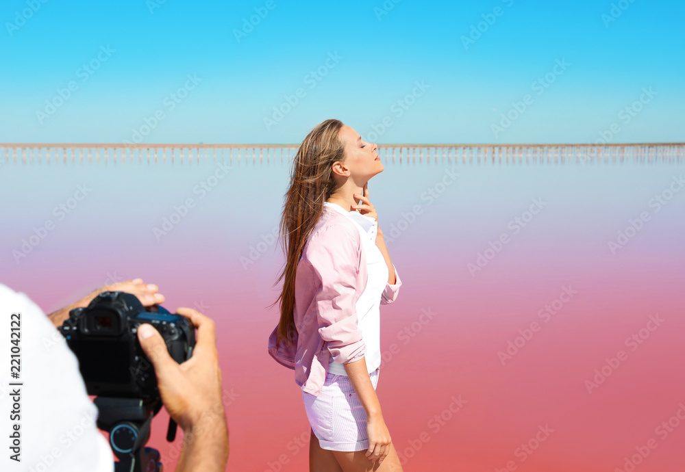 Wall mural Professional photographer taking photo of woman near pink lake on sunny day