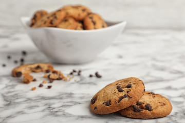 Tasty cookies with chocolate chips on marble table