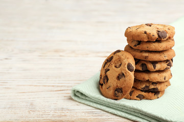 Stack of cookies with chocolate chips on wooden table, space for text