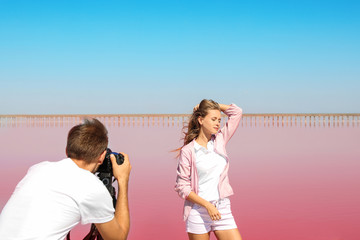 Professional photographer taking photo of woman near pink lake on sunny day