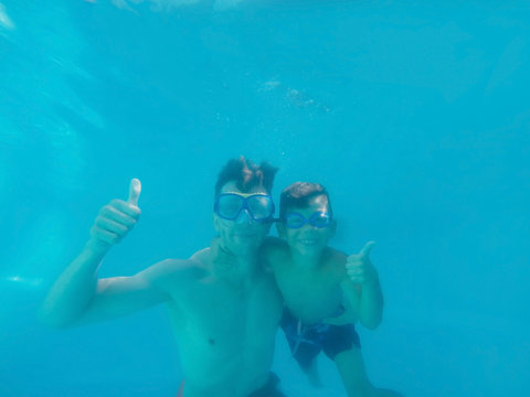 Father and son underwater in swimming pool