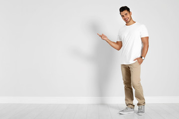 Full length portrait of handsome young man and space for text on white wall background