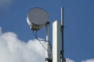 Cellphone telecommunication tower with clouds and blue sky