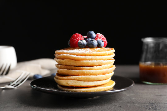 Tasty pancakes with berries and sugar powder on plate