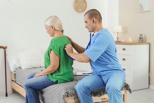 Male medical assistant examining female patient during home visit