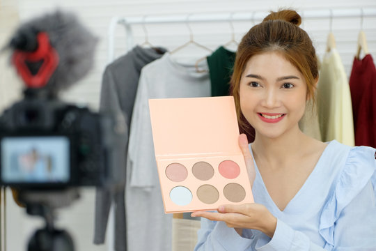 Young asian woman beauty blogger showing cosmetic recording how to make up video tutorial by camera, vlog concept, fashion people and technology communication