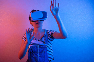 A cheerful girl with her hands up in virtual reality glasses.